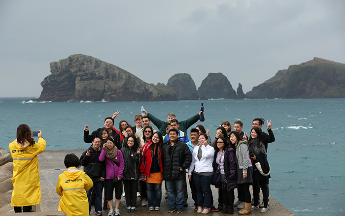 A group of tourists pose for a photo with Chagwido Island in the background.