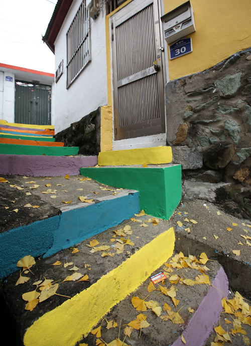 The Seopirang Village turns into a brighter, more cheerful neighborhood after the rundown walls and houses are repainted in brighter colors. 